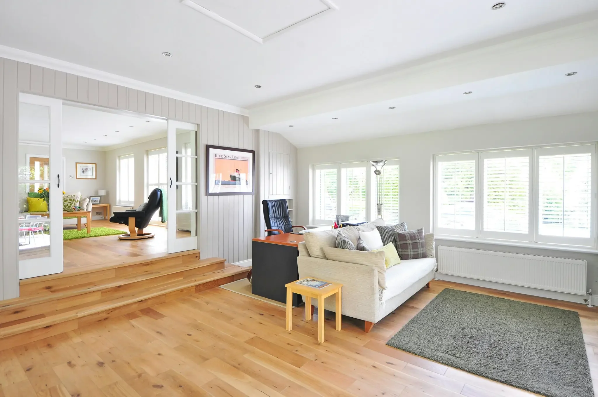 This open-concept space showcases creative hardwood floor designs, using a raised platform to define the office area from the main living room